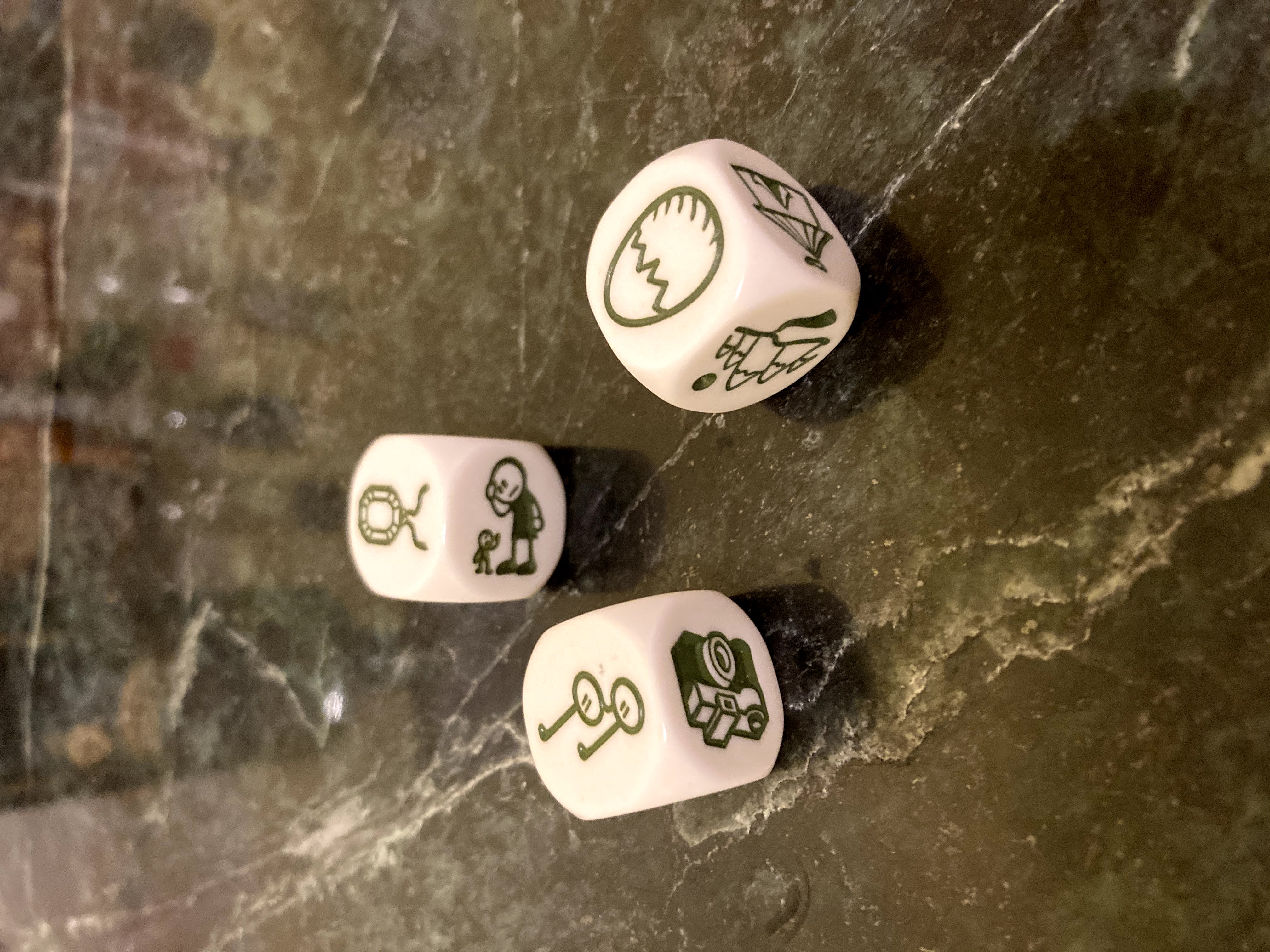 Three black and white story dice on a dark marble surface