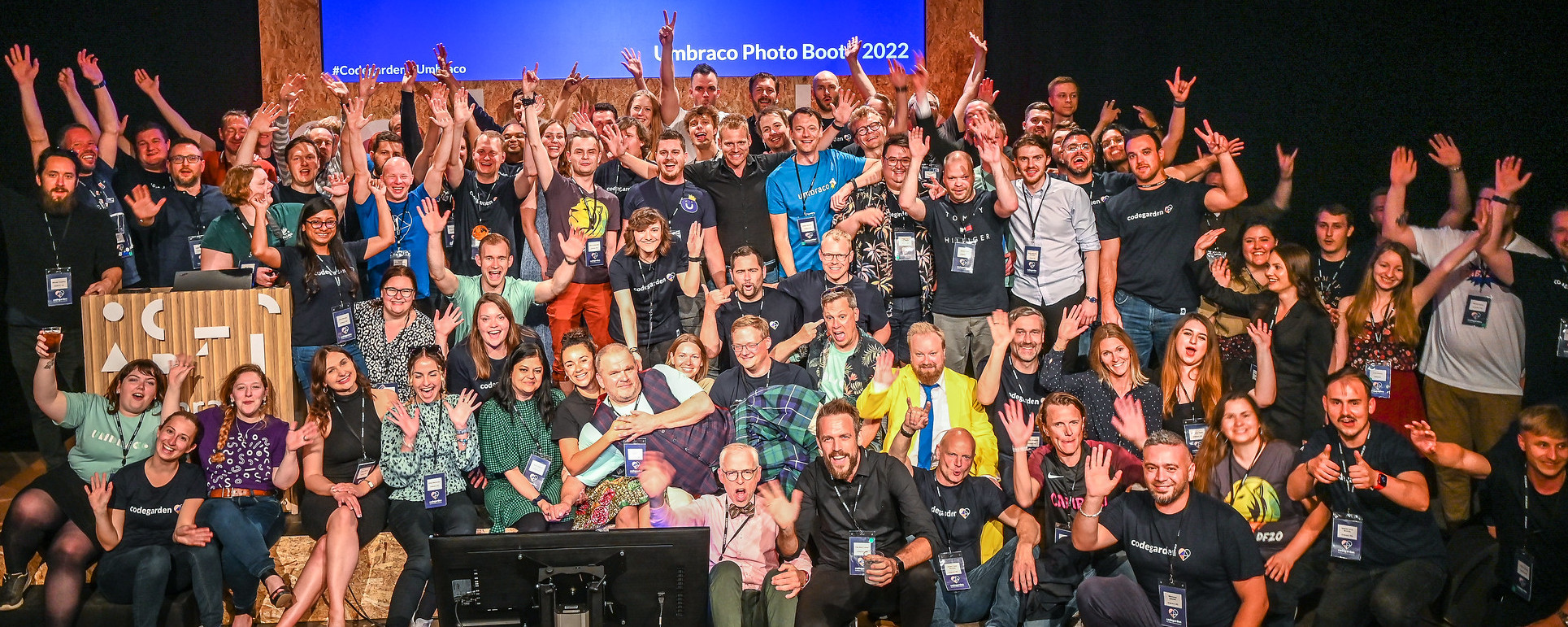 A group photo of HQ employees from Codegarden 2022. They have their hands raised in the air and are smiling and cheering.